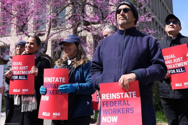 Rally where people are holding signs that say "Reinstate Federal Workers Now"