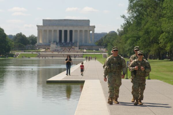 National Guard members in fatigues walking in front of the Lincoln Memorial.