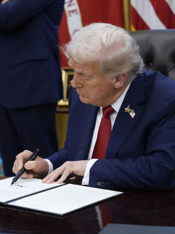 President Trump signs an executive order in the Oval Office of the White House.