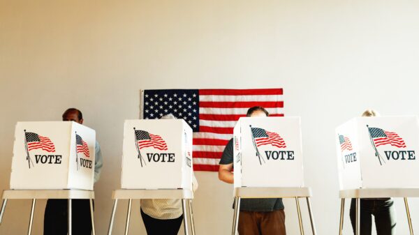 US election day, Diverse people at voting booth at US election station with American flag in background. Diverse people in line to vote at US election day. Vote for American democracy.