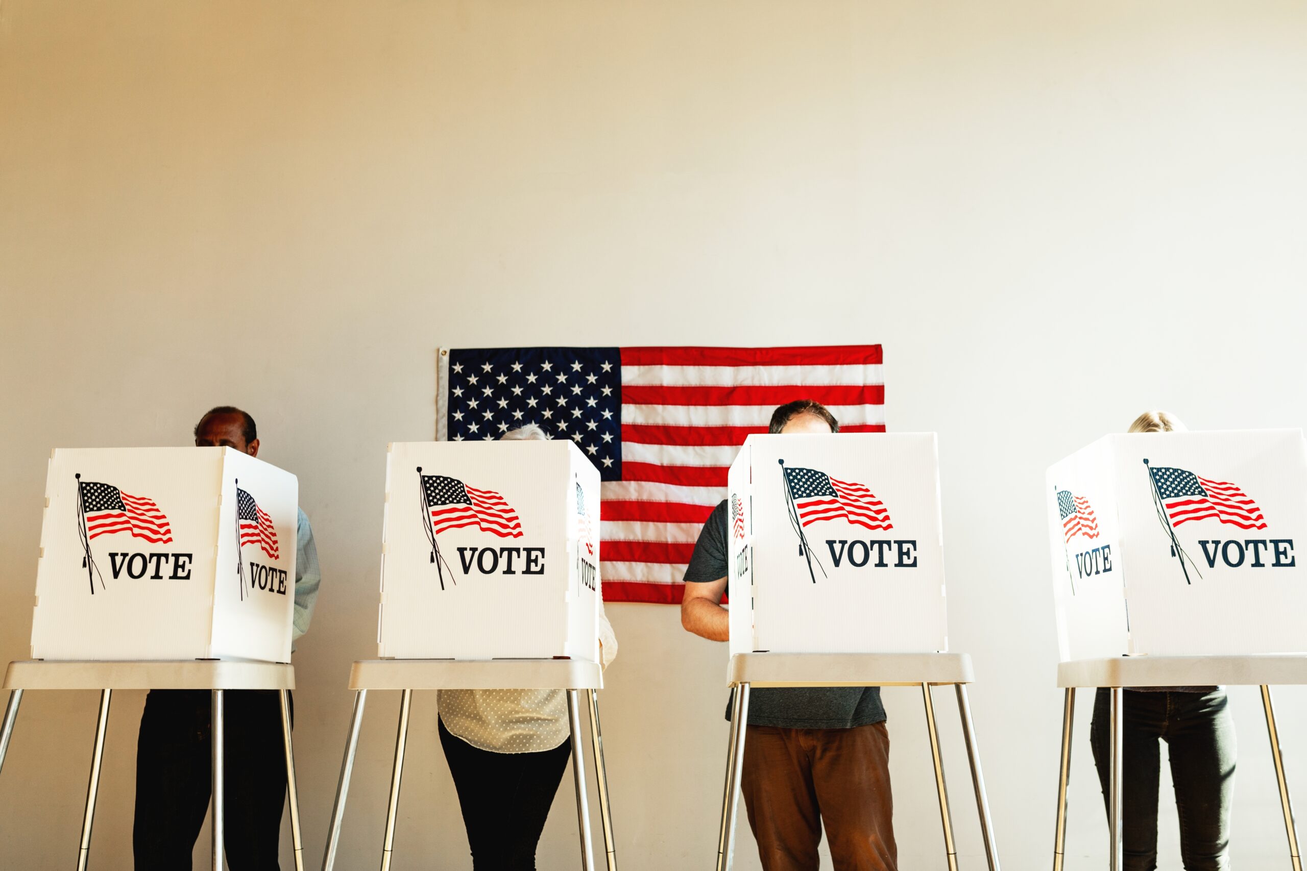 US election day, Diverse people at voting booth at US election station with American flag in background. Diverse people in line to vote at US election day. Vote for American democracy.