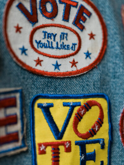 Patches on denim fabric. The patches read "Vote. You'll like it." and "Vote."