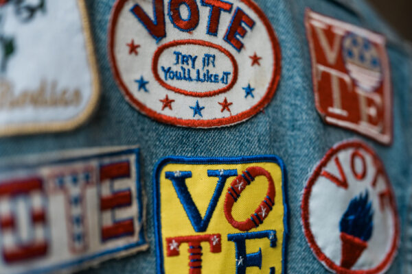 Patches on denim fabric. The patches read "Vote. You'll like it." and "Vote."