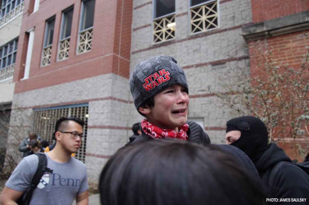 a young boy is being carried away by his mother after being exposed to pepper spray