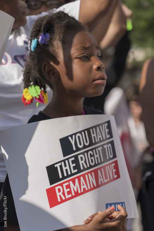 young girl holding sign that reads "you have the right to remain alive"