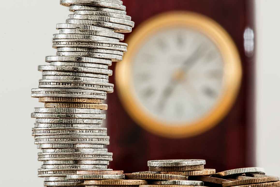 stack of coins with clock in background to illustrate a budget