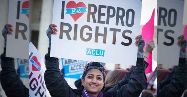 Smiling person holding an "I heart Repro Rights" sign