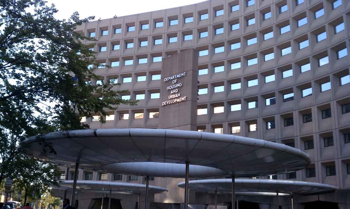 Image description: photo taken of the United States Department of Housing and Urban Development building, taken with a wide angle to show the building sign and offices in the background